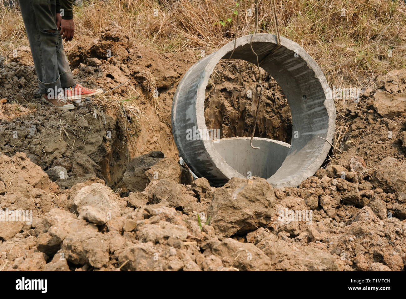 worker burying pipe on ground for making septic tank at construction