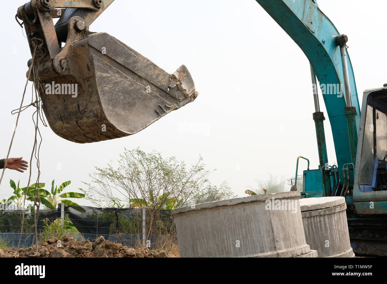 excavator backhoe tractor putting pipe on ground at construction site