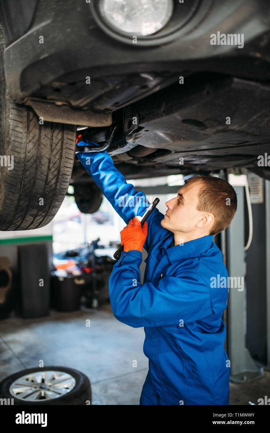 A car mechanic inspects shock absorber, springs and stabilizer bars with a  flashlight. Car on a repair stand. Technical service station for car Stock  Photo - Alamy