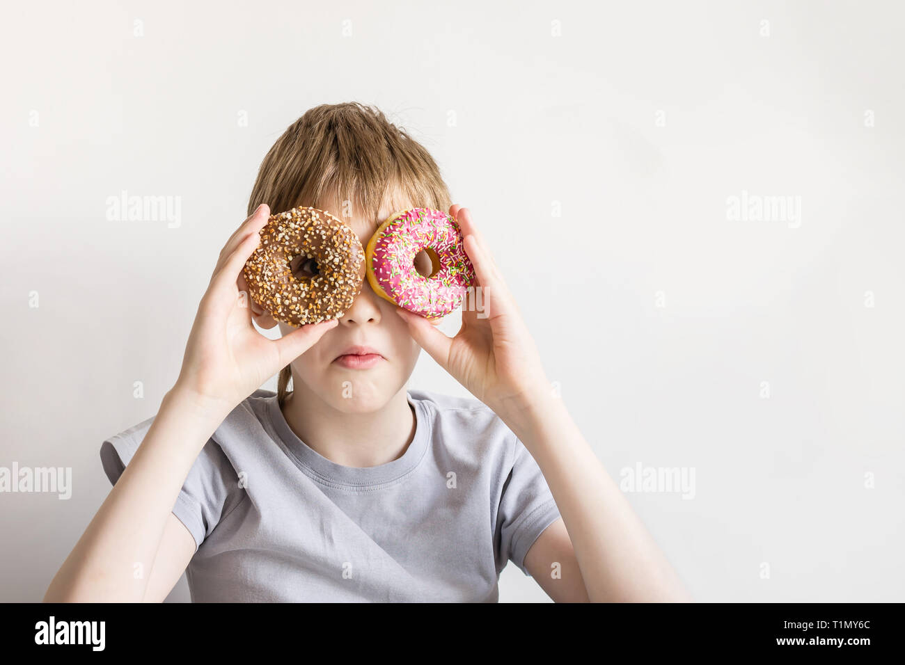 Teen boy looks into donut holes and funny grimaces. Stock Photo