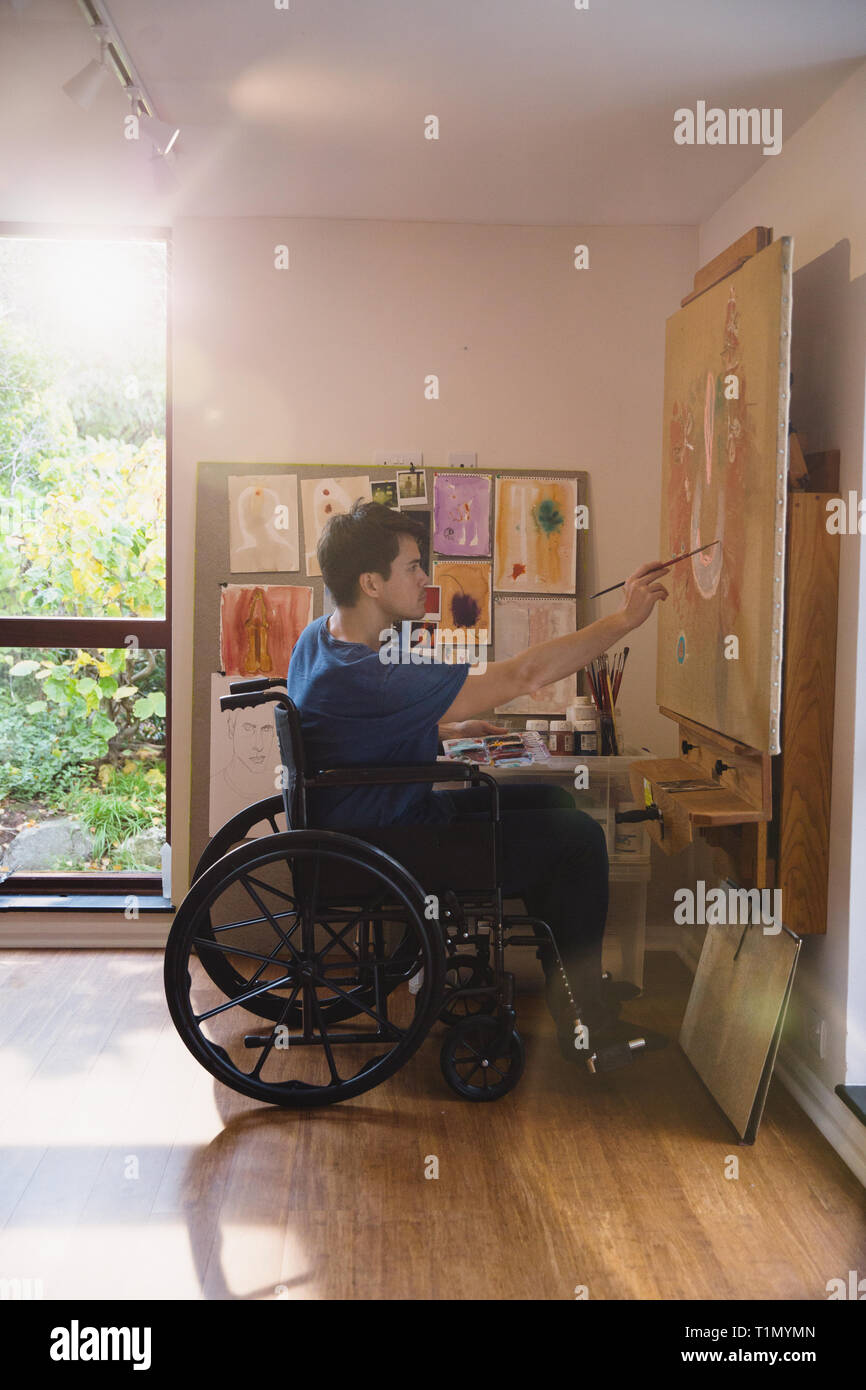 Male artist in wheelchair painting in art studio Stock Photo