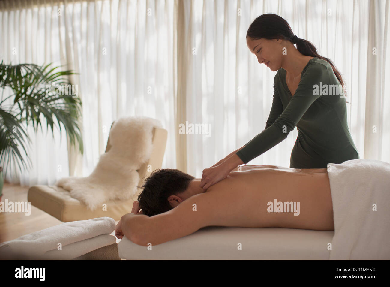 Female masseuse giving man massage Stock Photo -