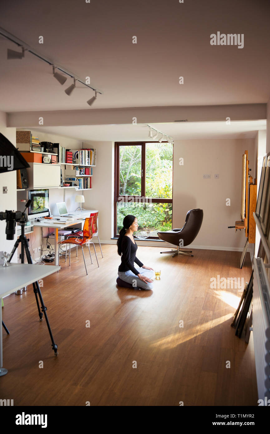 Young woman meditating in home office Stock Photo