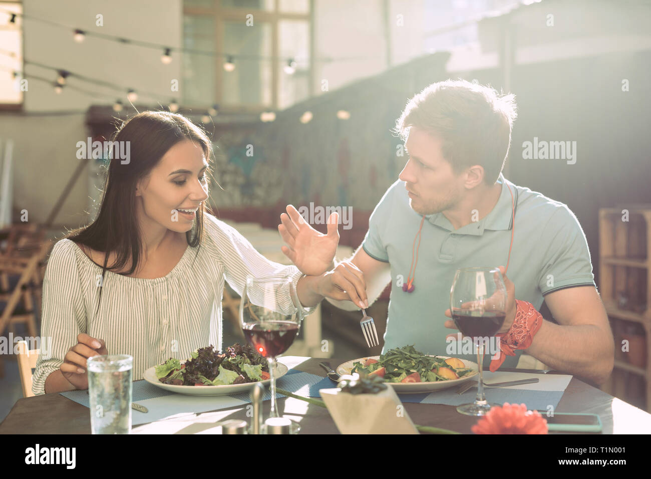Shameless long-haired girl stealing pieces of salad from plate Stock Photo