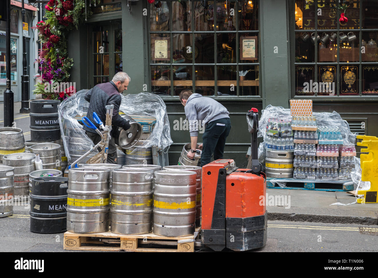 Two men at work moving a delivery of beer kegs into the cellar of Mr