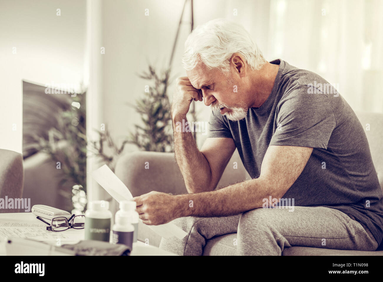 Aging mister clutching his head in despair while holding papers Stock ...