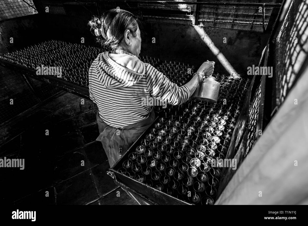 Kathmandu, Nepal - November 22, 2015: Old woman prepares incense butter candles. Boudhanath stupa in Kathmandu, Nepal. Black and white image. Stock Photo