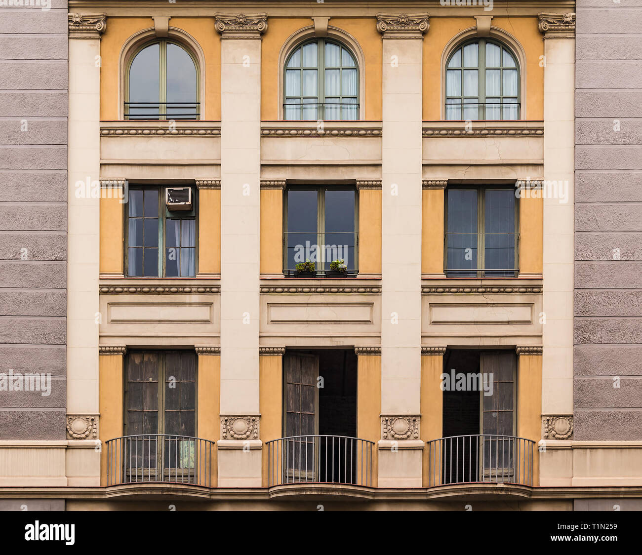 Several windows and balconies in a row on the facade of the urban historic building front view, Barcelona, Spain Stock Photo
