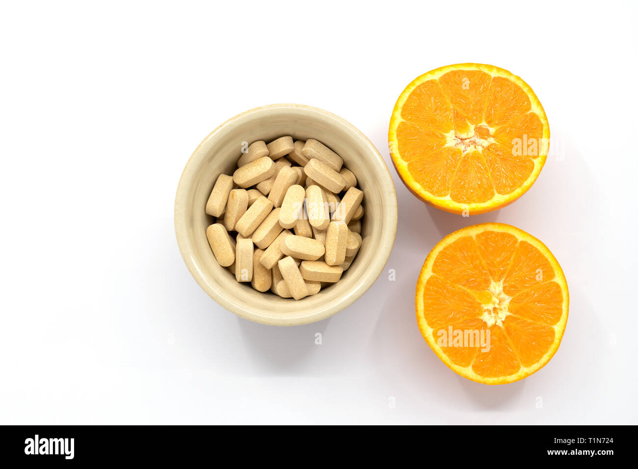 pot of vitamin c tablets with an orange cut in half Stock Photo