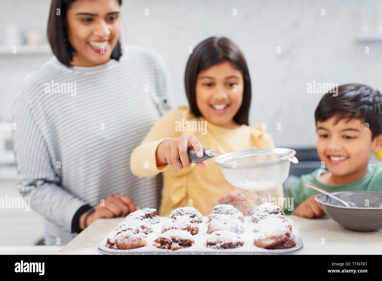 Mother and children baking muffins in kitchen Stock Photo