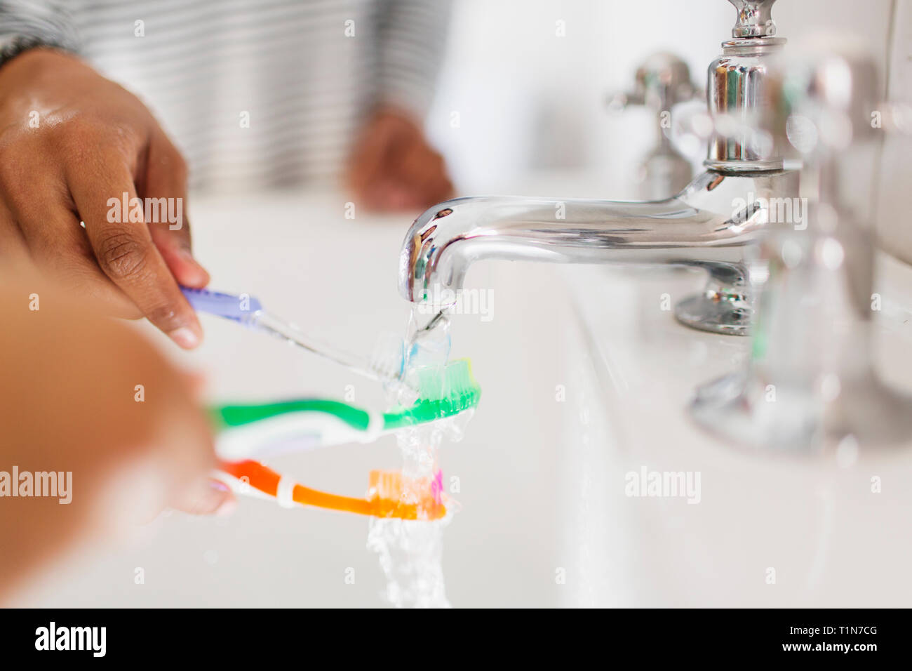 Close up family rinsing toothbrushes in bathroom sink Stock Photo