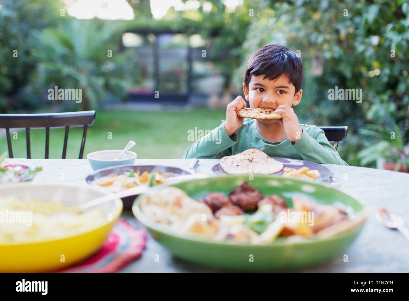 Boy eating naan bread at dinner table Stock Photo