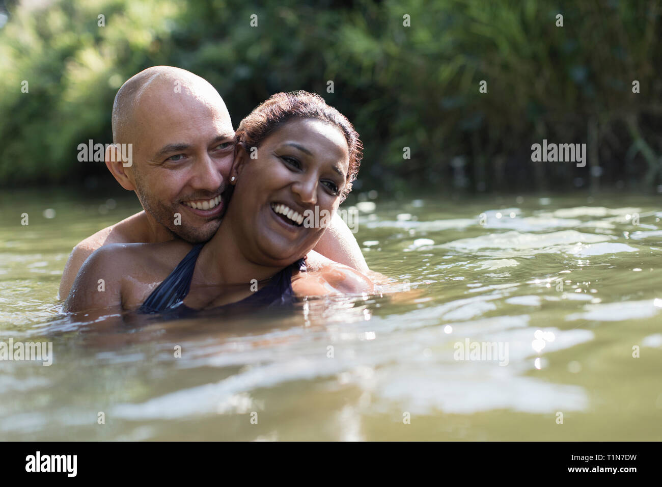 Happy, affectionate couple in sunny river Stock Photo