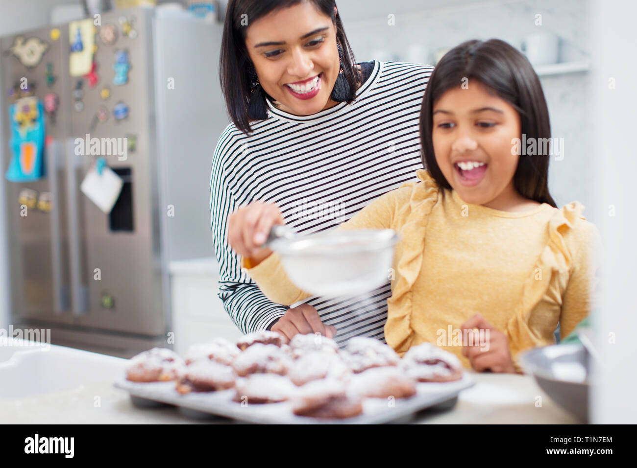 Mother and daughter baking muffins in kitchen Stock Photo