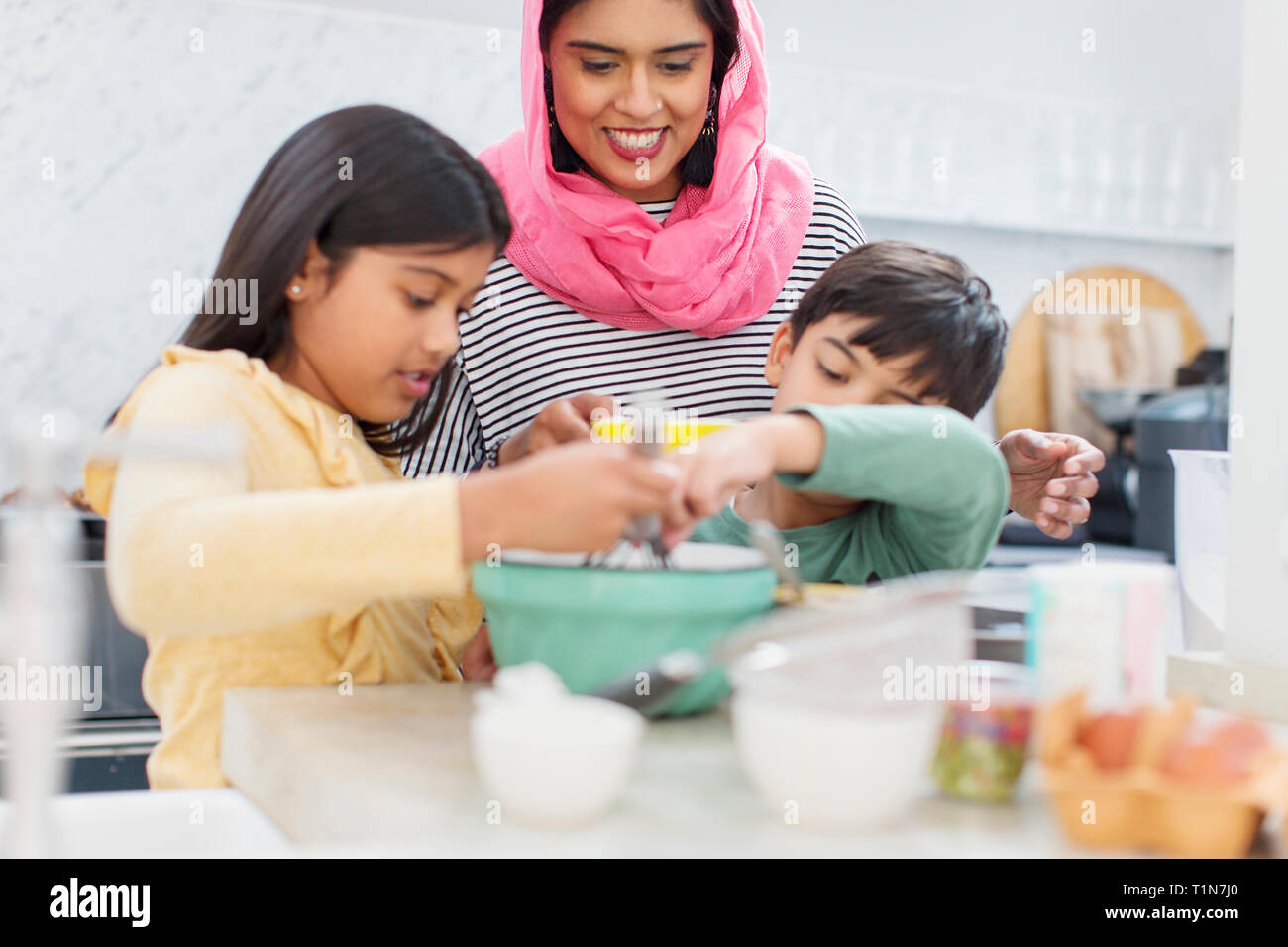 Mother in hijab baking with children in kitchen Stock Photo