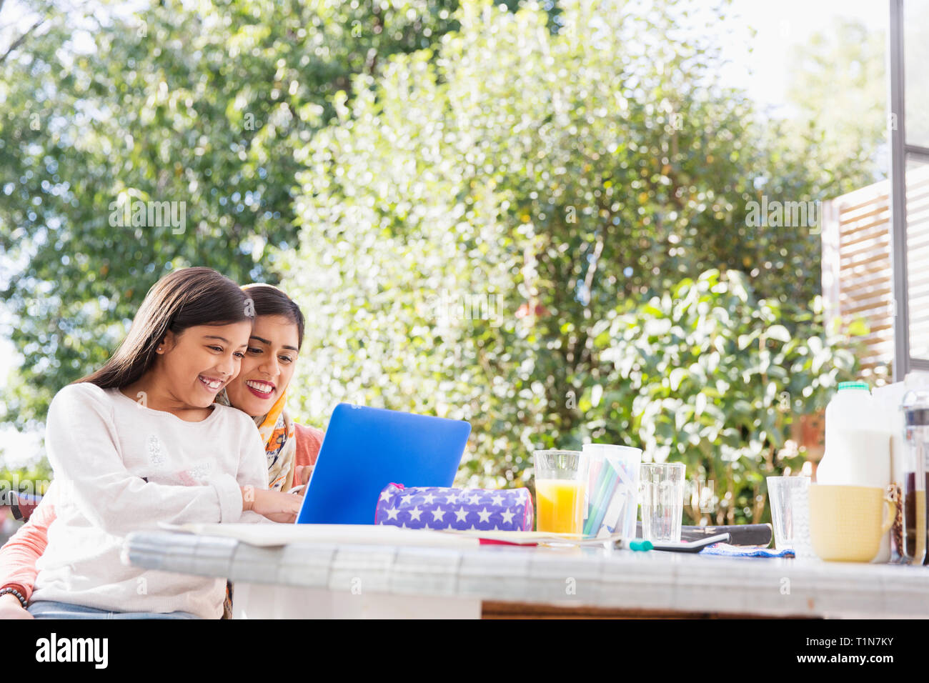 Smiling mother and daughter using laptop at table Stock Photo