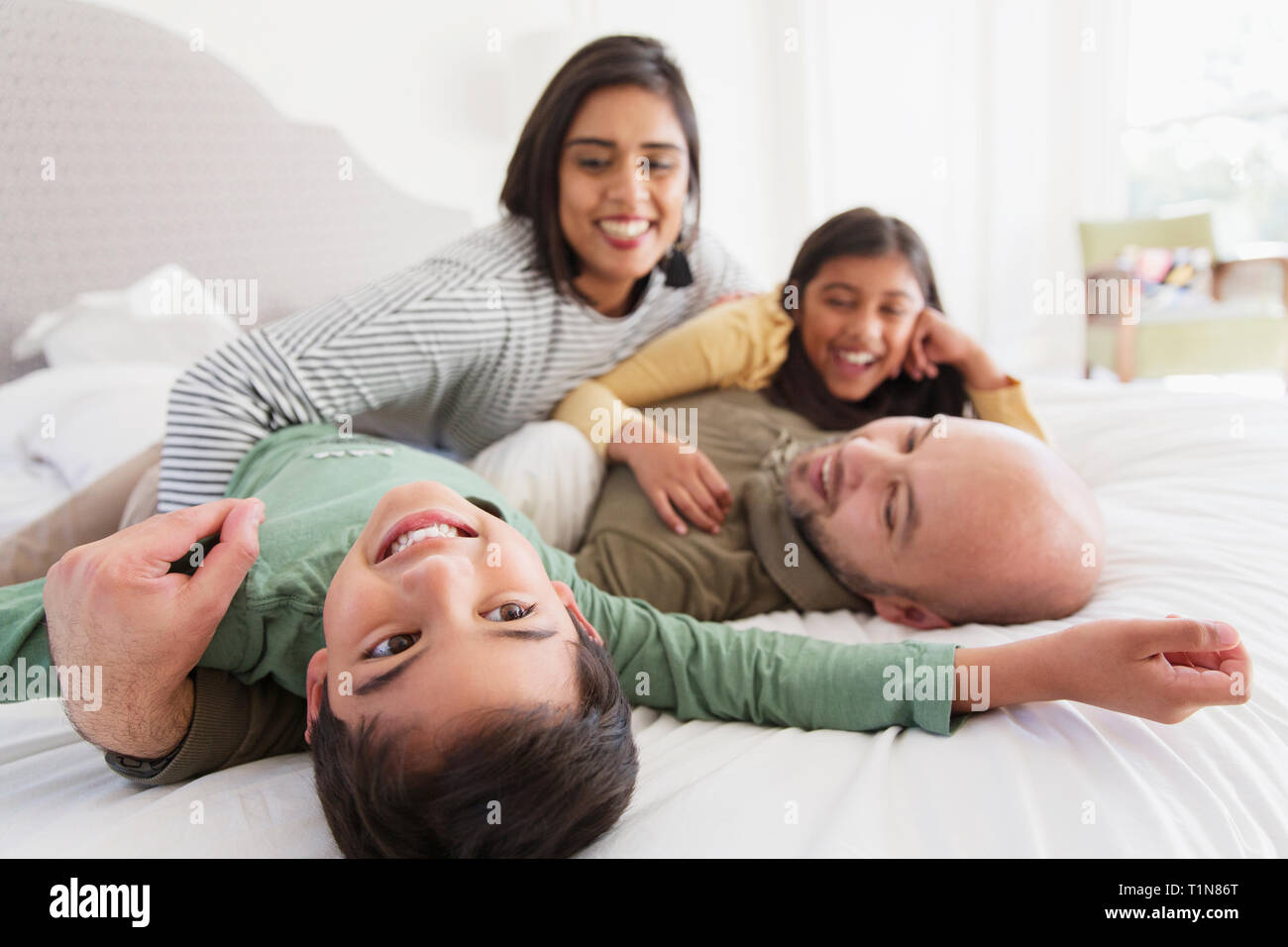 Happy family cuddling on bed Stock Photo