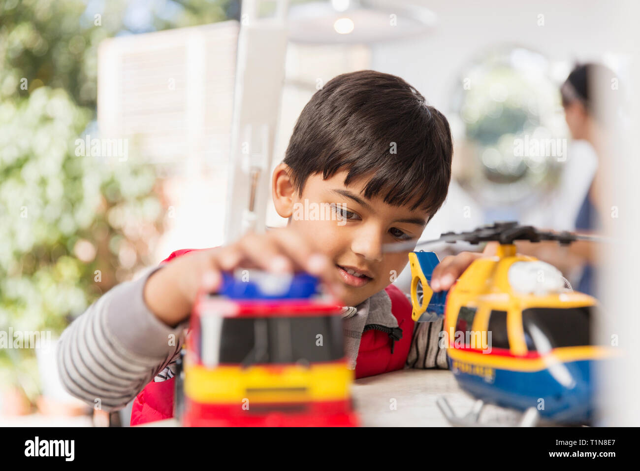 Boy playing with toy helicopter and fire engine Stock Photo