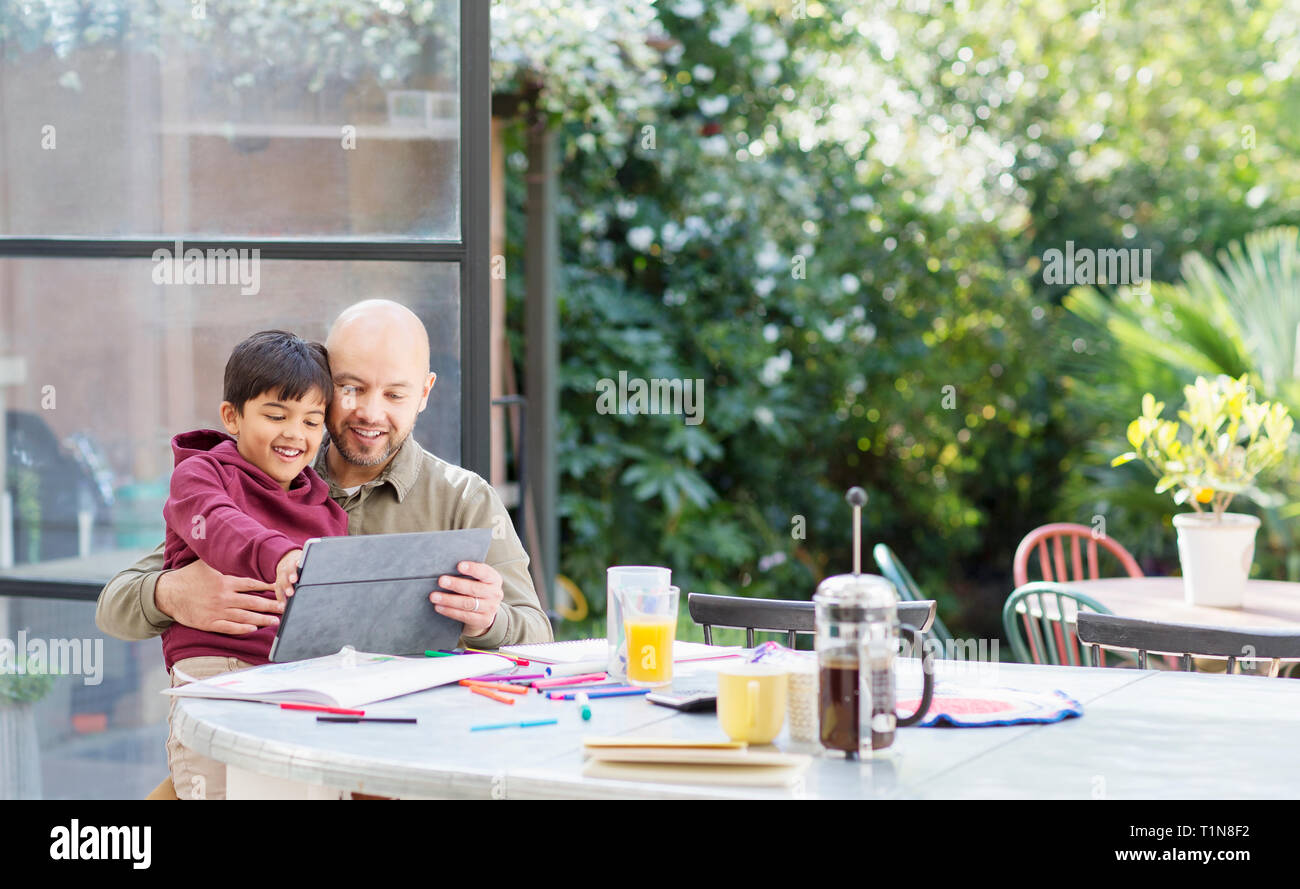 Father and son using digital tablet at table Stock Photo