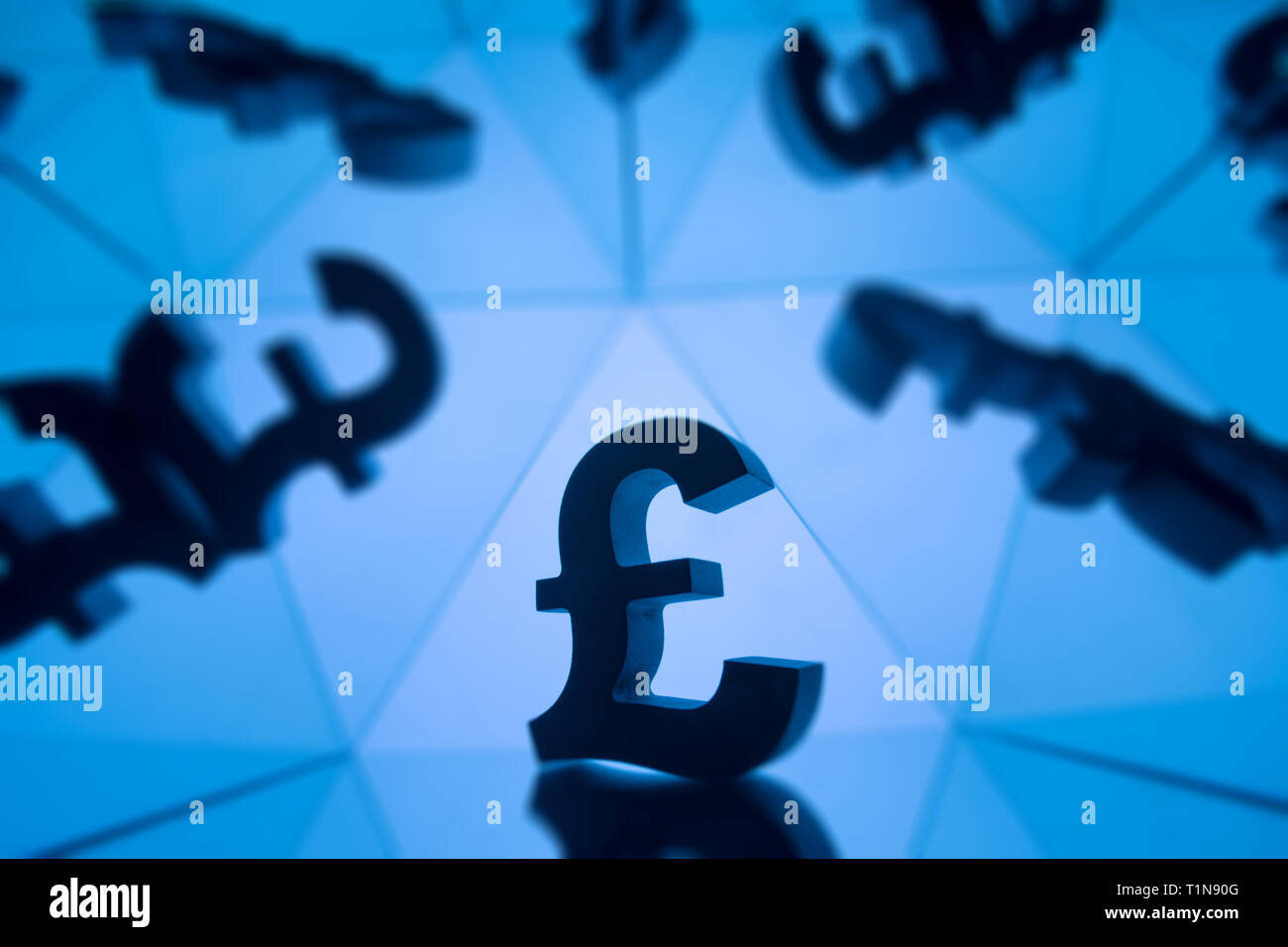 British Pound Sterling Currency Symbol With Many Mirroring Images of Itself on Blue Background Stock Photo
