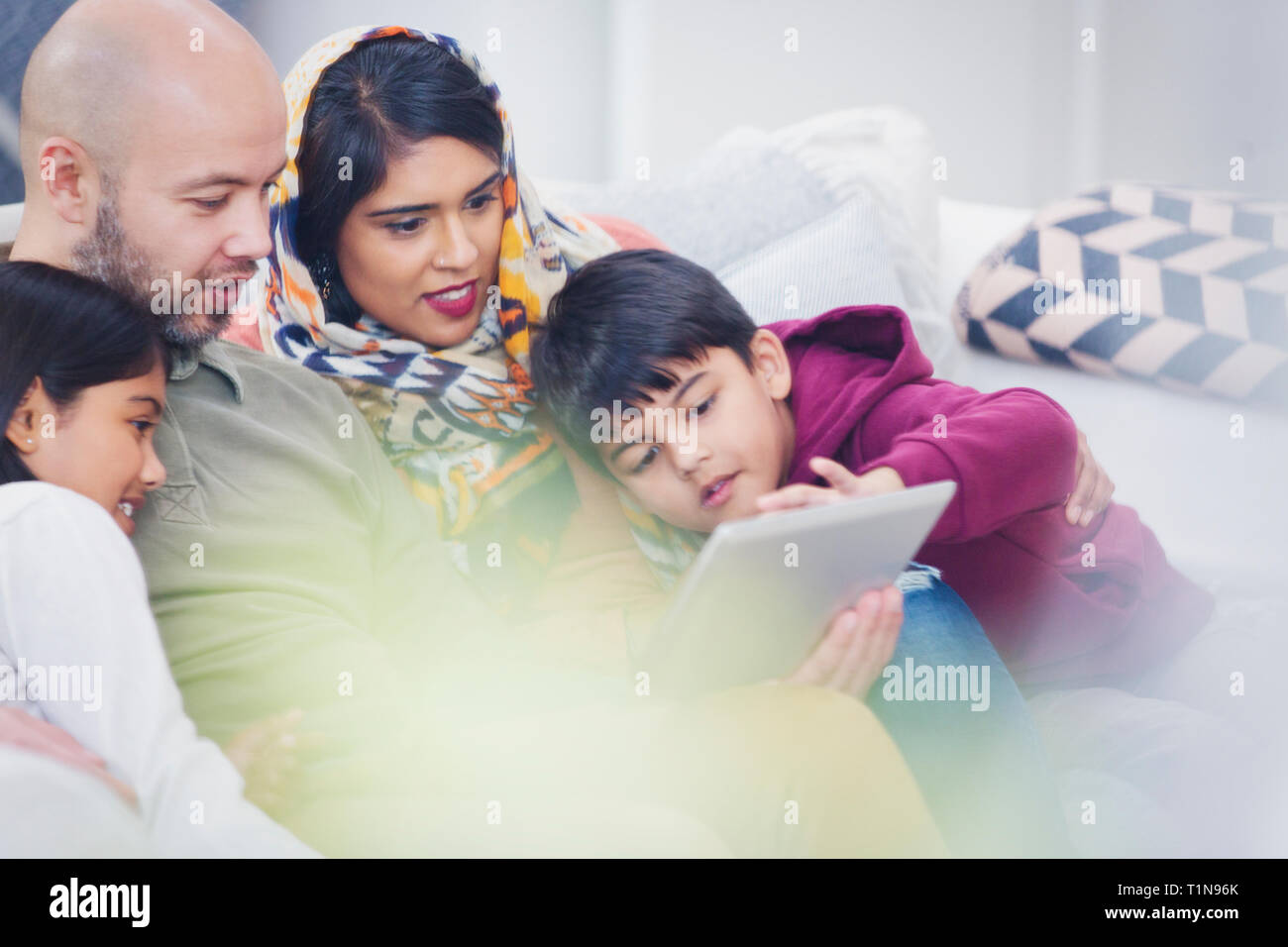 Family using digital tablet on living room sofa Stock Photo