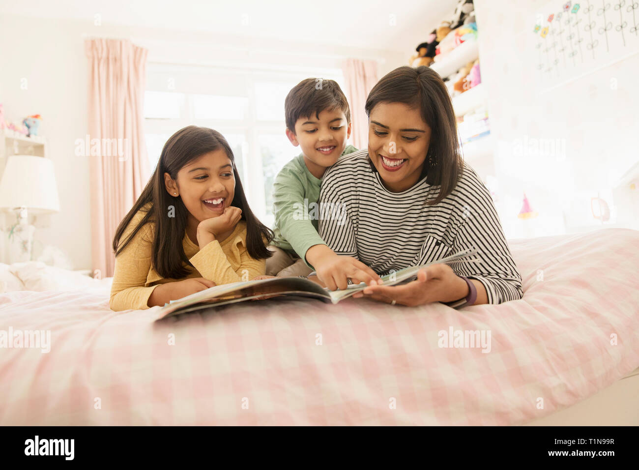 Mother reading book to children on bed Stock Photo