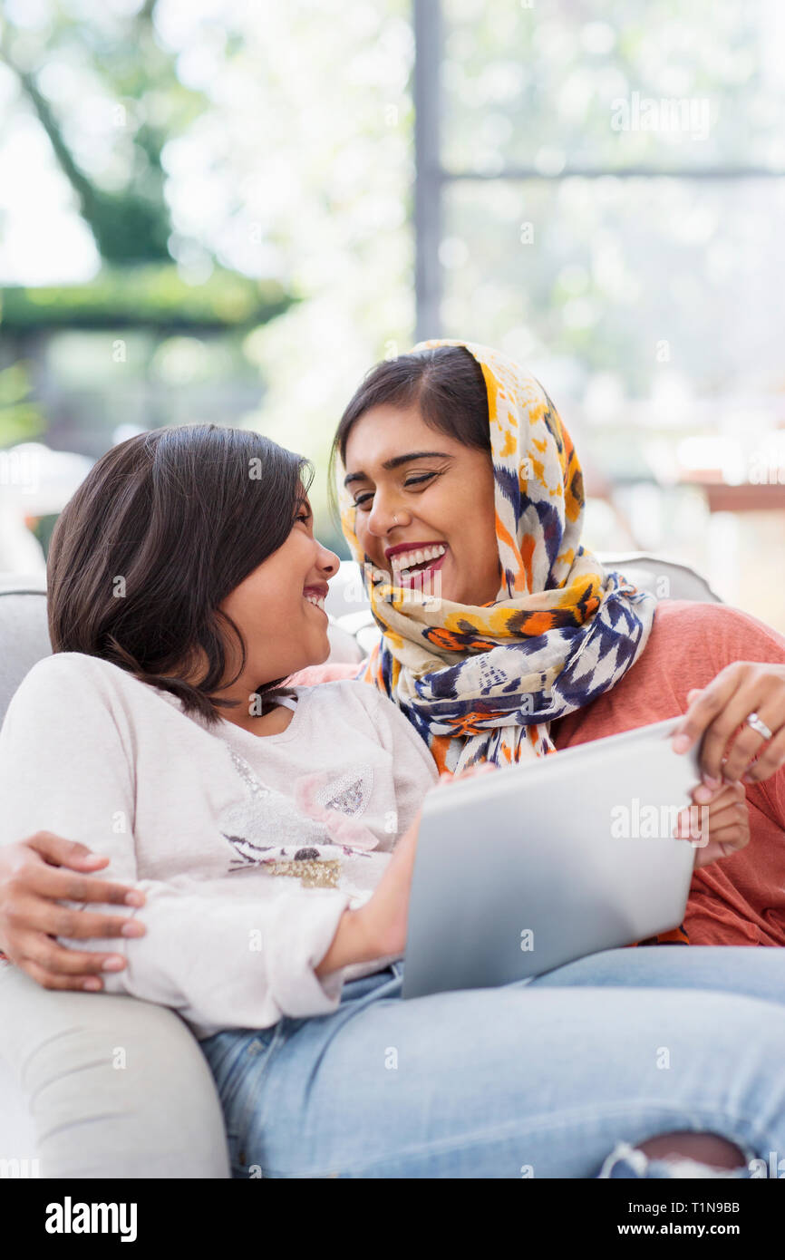 Happy mother in hijab using digital tablet with daughter Stock Photo