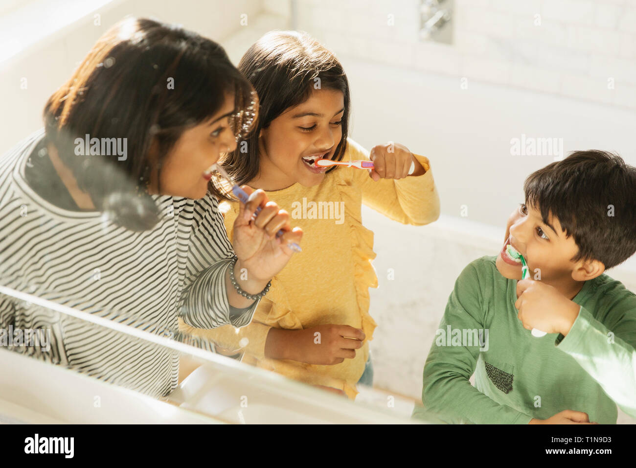 Mother and children brushing teeth in bathroom Stock Photo