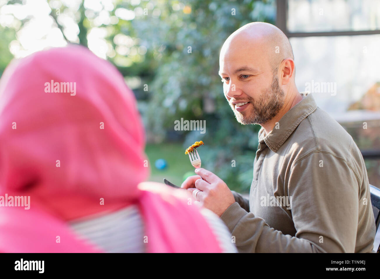 Man eating with wife in hijab Stock Photo