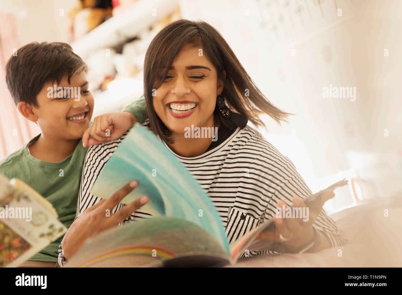 Happy mother and son reading books on bed Stock Photo