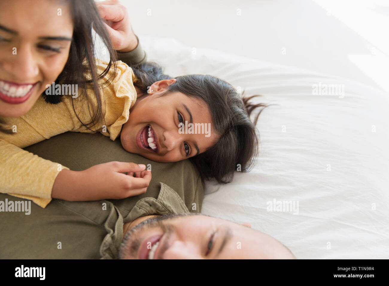 Portrait happy parents and daughter cuddling on bed Stock Photo
