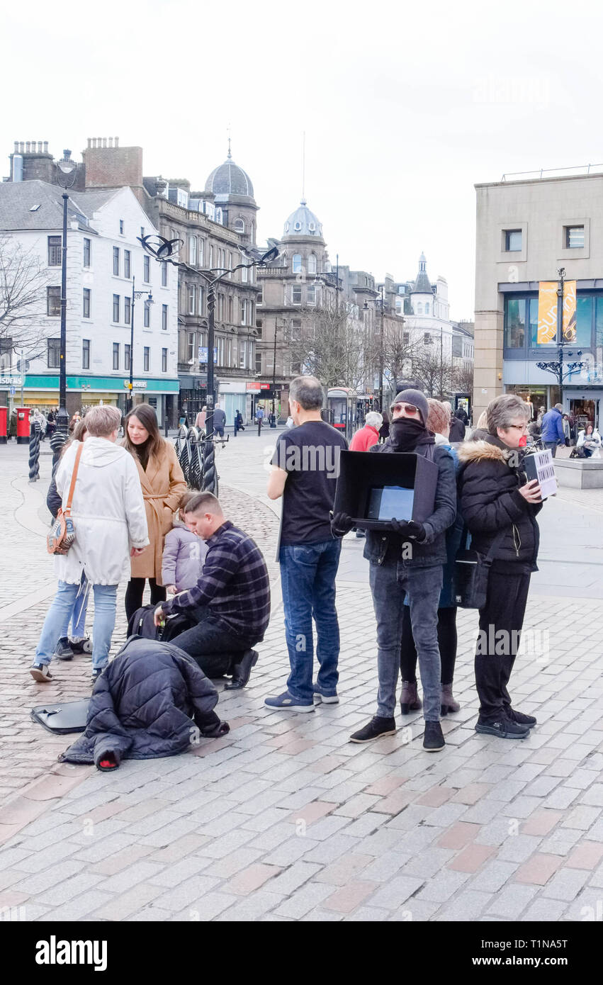 Dundee, Scotland, UK - March 23, 2019: Some people protest with partial facial coverings e.g Plastic tape and head scarfs over mouths holding 'Watch D Stock Photo