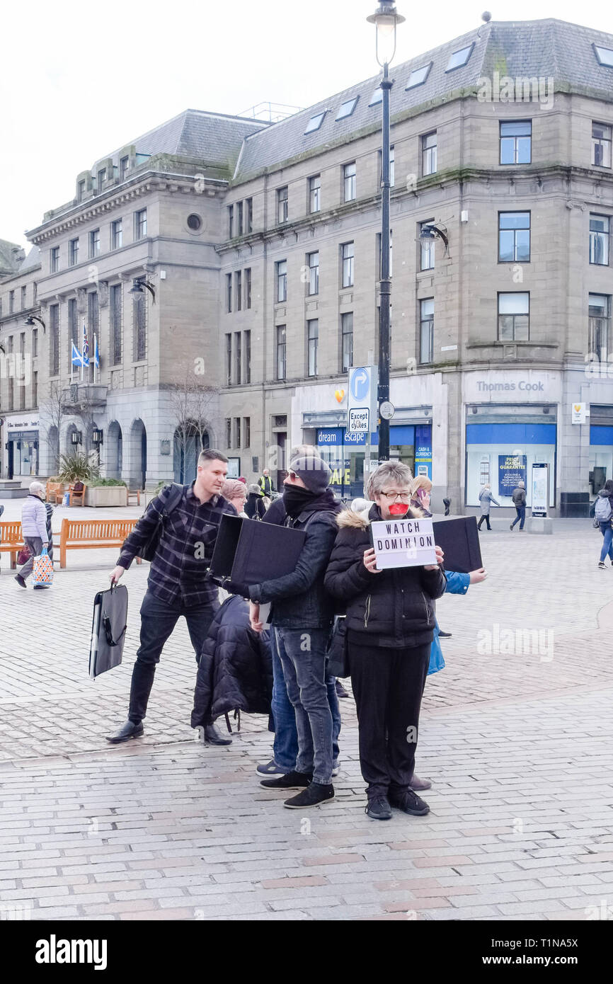 Dundee, Scotland, UK - March 23, 2019: Some people protest with partial facial coverings e.g Plastic tape and head scarfs over mouths holding 'Watch D Stock Photo