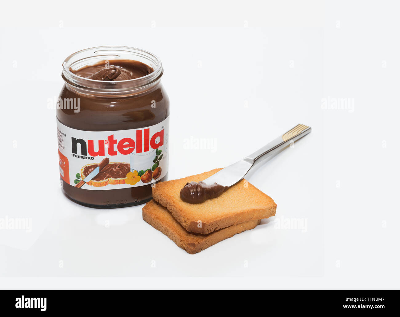 jar of chocolate nutella cream with knife on grey background Stock