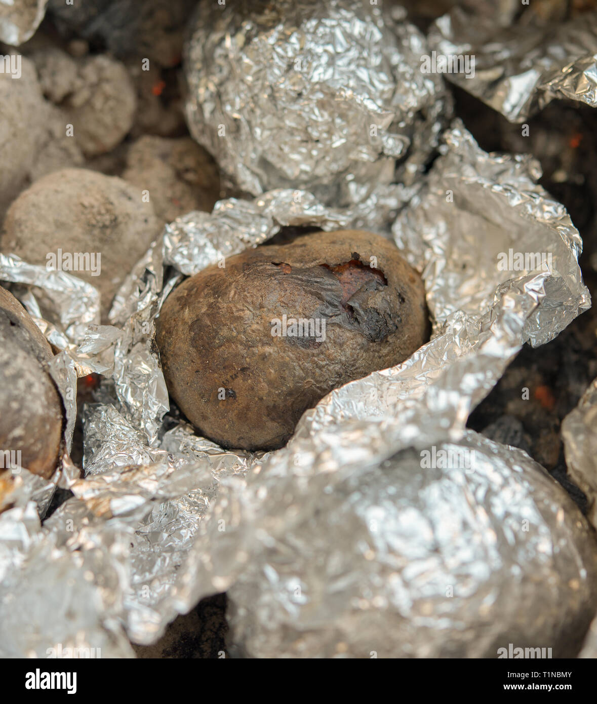 potatoes in aluminum foil cooked under the charcoal embers Stock Photo Alamy