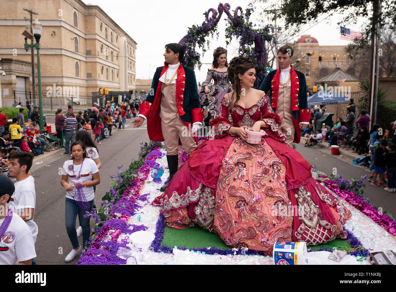 Local debutantes and their escorts wear elaborate costumes while riding