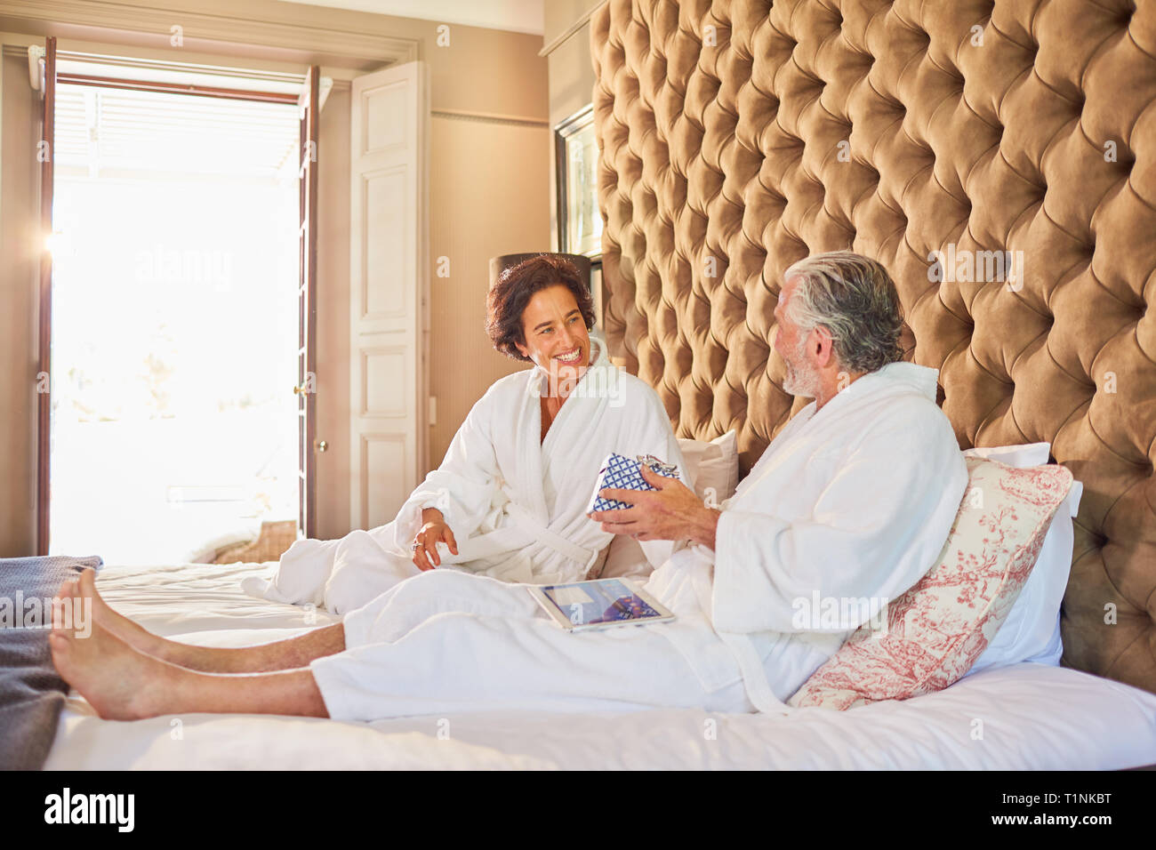 Mature couple in bathrobes on hotel bed Stock Photo