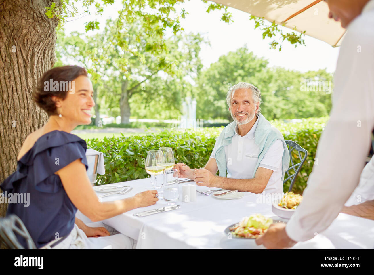 Waiter serving food to mature couple dining at patio table Stock Photo