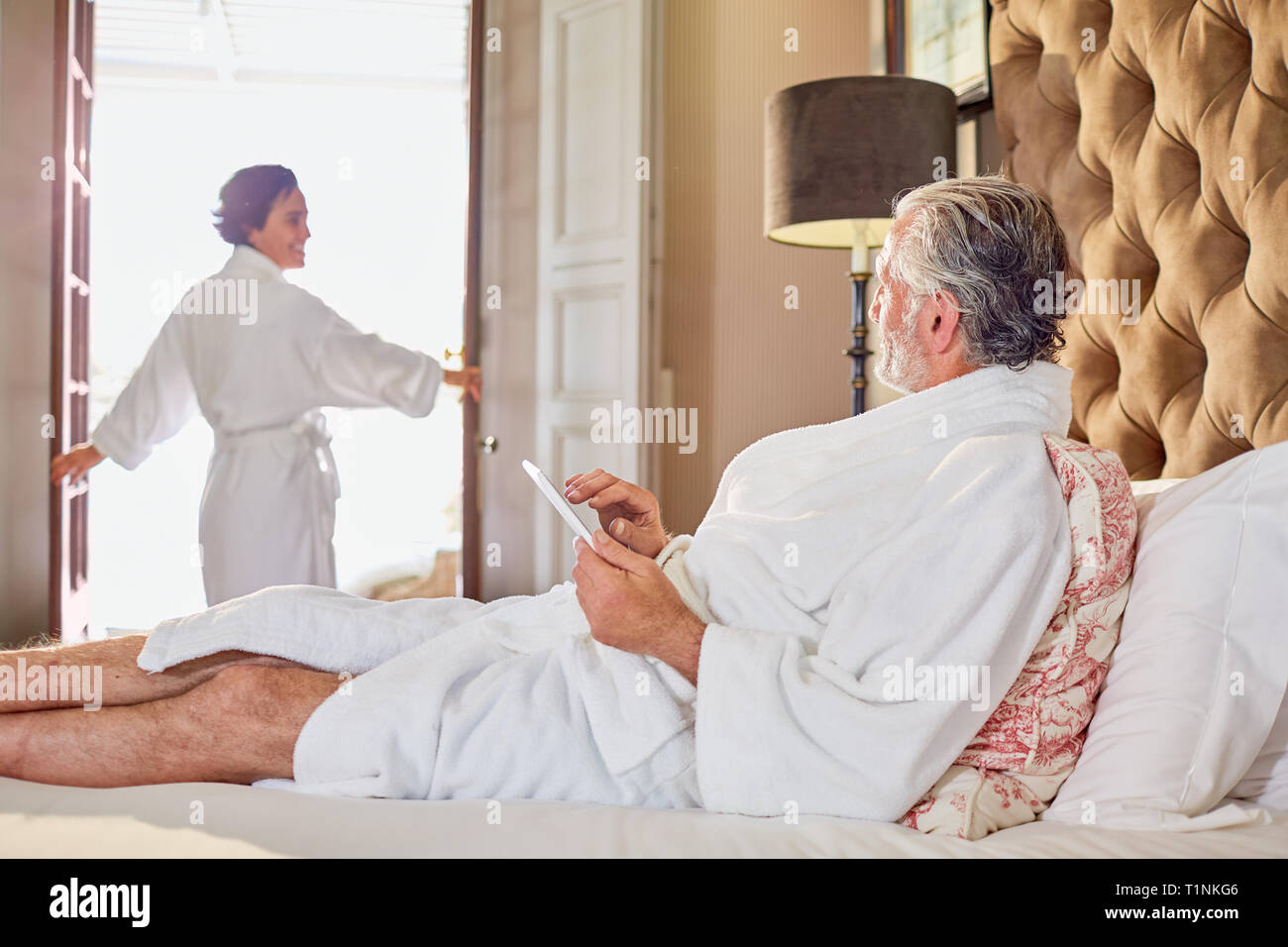 Mature couple in bathrobes relaxing in hotel room Stock Photo