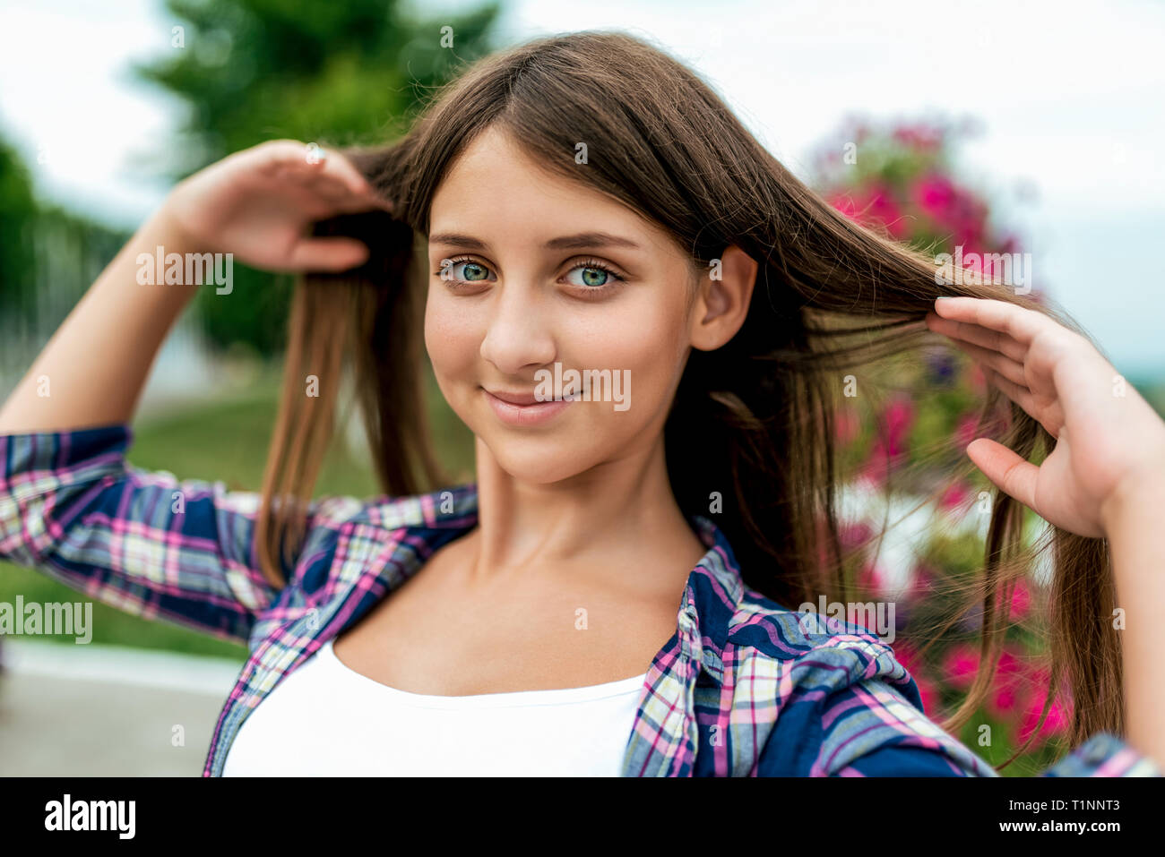 Beautiful Girl Student 13 16 Years Old In The Summer In The Park In The Fresh Air Straightens Long Hair Happy Smiles Close Up Shirt Shirt Flowers Stock Photo Alamy