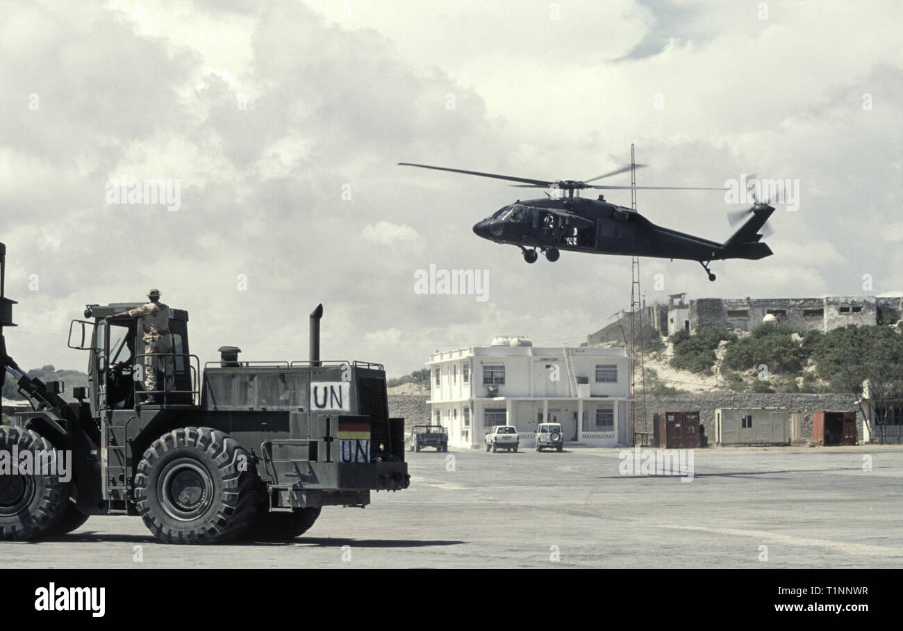 29th October 1993 A U.S. Army Sikorsky UH-60 Black Hawk helicopter coming in to land in the new port in Mogadishu, Somalia. On the left is a Caterpillar (Cat) 988B/DV43 Container Handler. Stock Photo