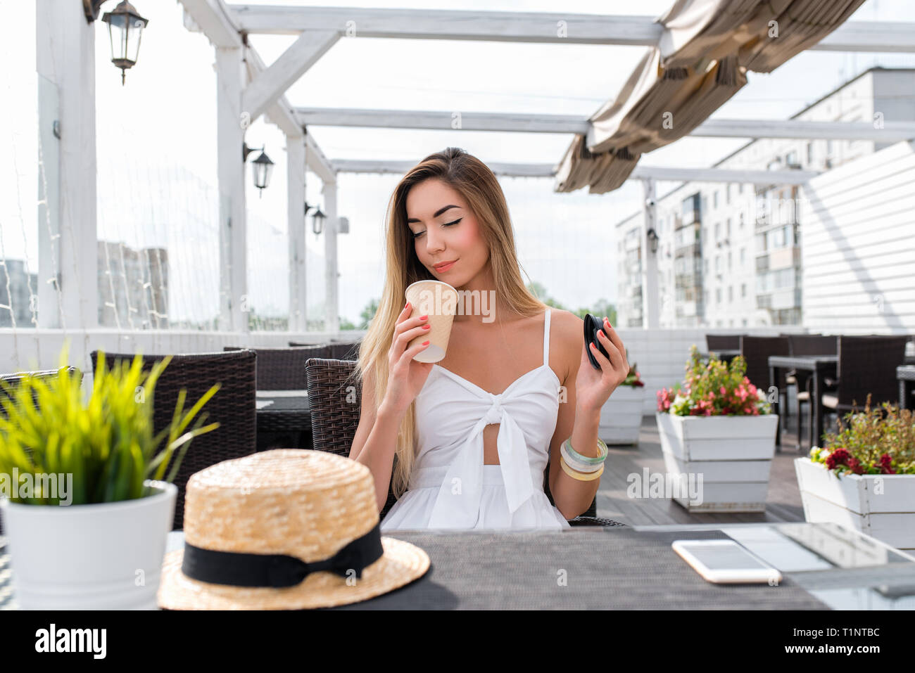 The girl in the cafe. Sniffs and enjoys coffee, inhales the aroma gets pleasure from the smell of tea. Relaxing summer restaurant on the veranda Stock Photo