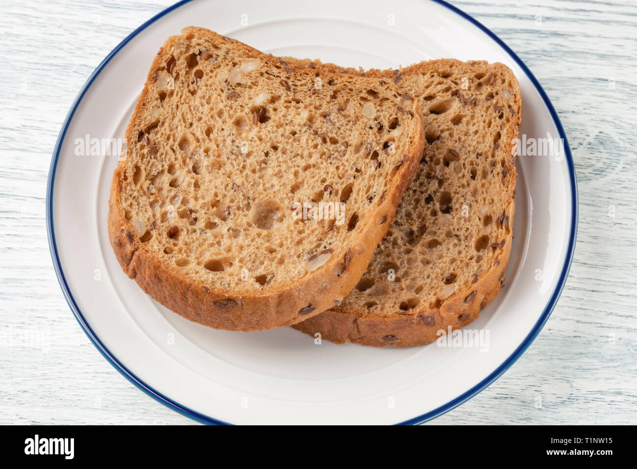 Slices Of Grain Bread With Mold On A White Plate With A Blue Stripe