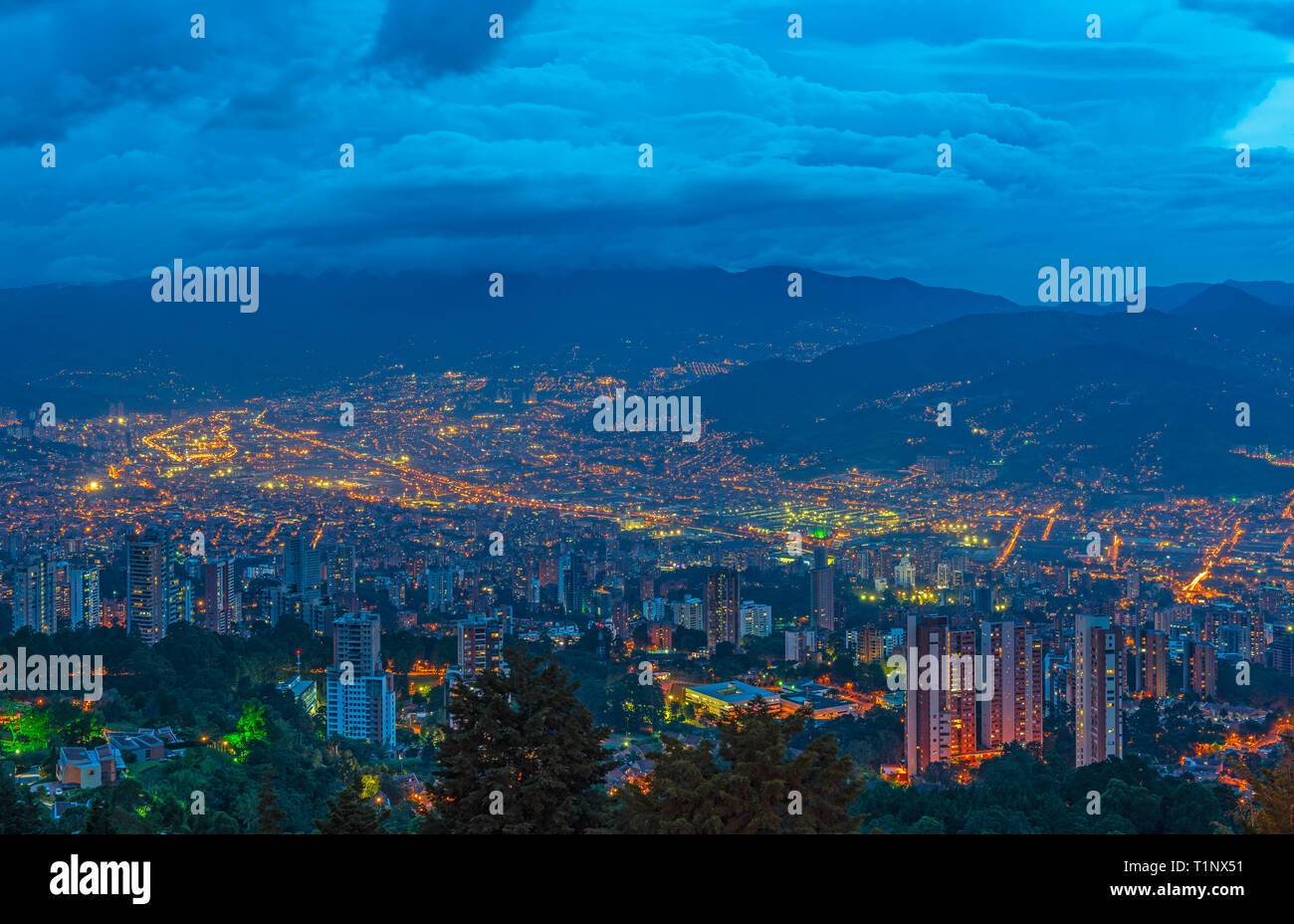 Cityscape of Medellin city at night (blue hour) with its modern skyscraper architecture located in a valley of the Andes mountain range, Colombia. Stock Photo