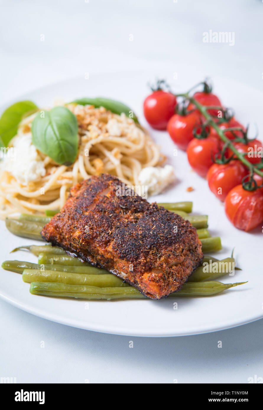 Cod Fish Green Meat Close up view of blackened cod fish with green vegetables, tomatoes ...