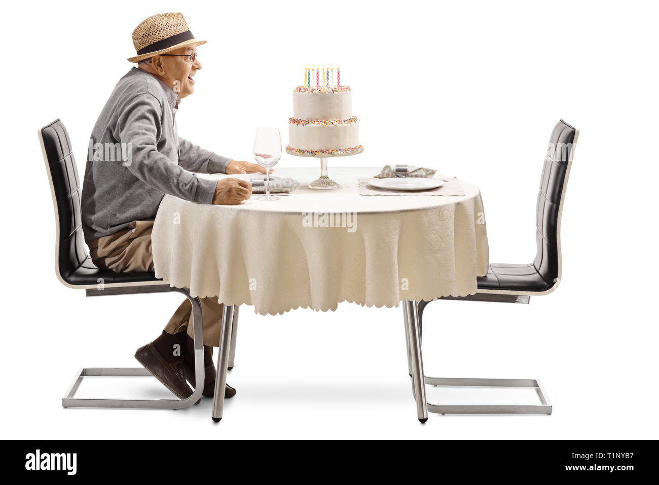Excited senior man with a birthday cake at a restaurant table isolated on white background Stock Photo