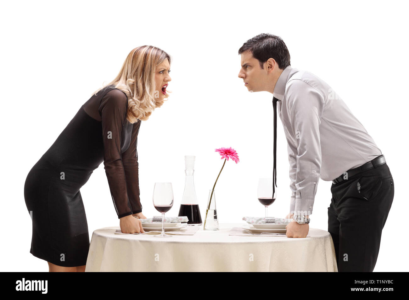 Young man and woman having an argument at a restaurant table isolated on white background Stock Photo