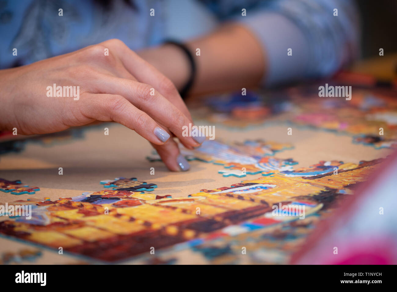 A woman and child's hands solving a jigsaw puzzle. Stock Photo