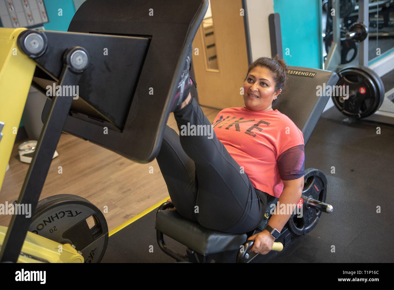 A woman uses a leg press machine at a gym UK Stock Photo ...