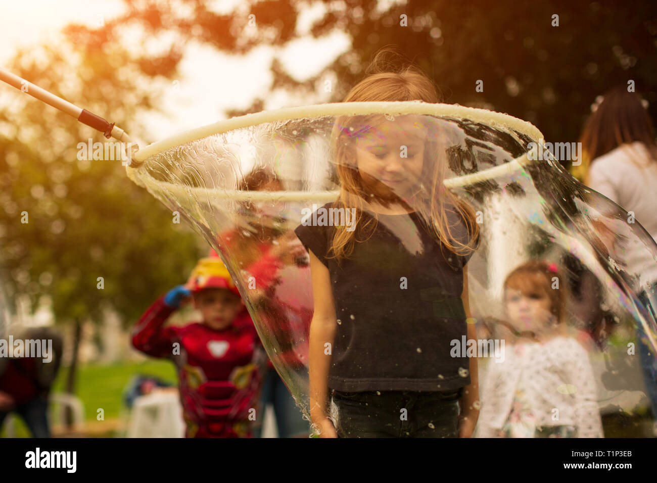 Baby girl stands in a huge soap bubble on, a holiday fun for children Stock Photo